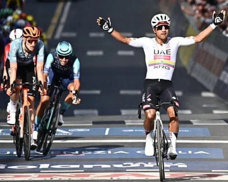 Jhonatan Narváez raises his arms after the finish line as other sprinters keep racing